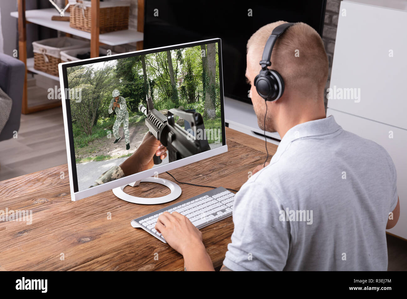 Junger Mann spielen Action Spiel auf dem Computer über Holz- Schreibtisch Stockfoto