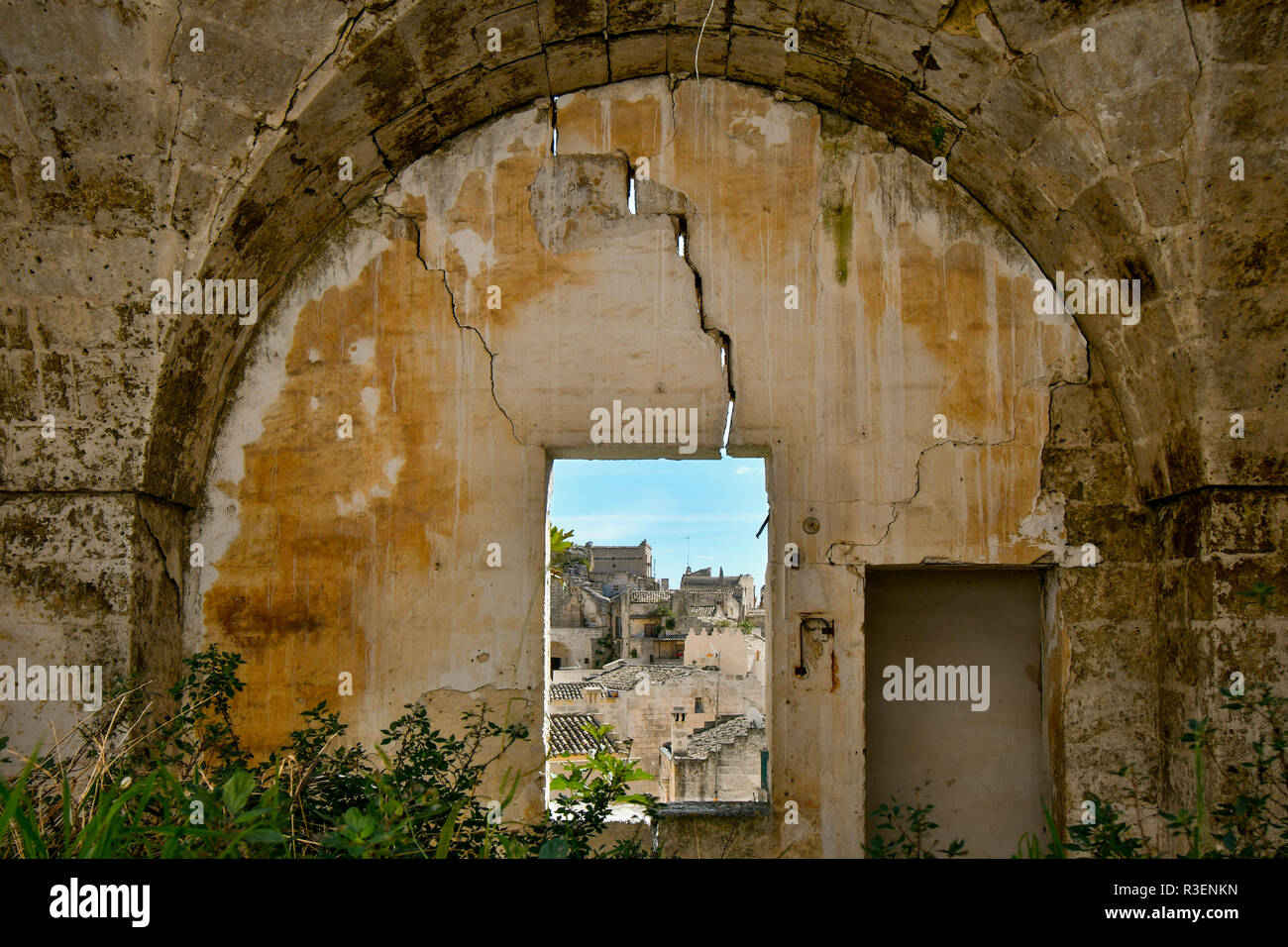 Eine Steinmauer mit Fenster bietet einen Blick auf die antiken Sassi Höhlen und Stadt Matera, im Süden Italiens in der Region Basilicata. Stockfoto