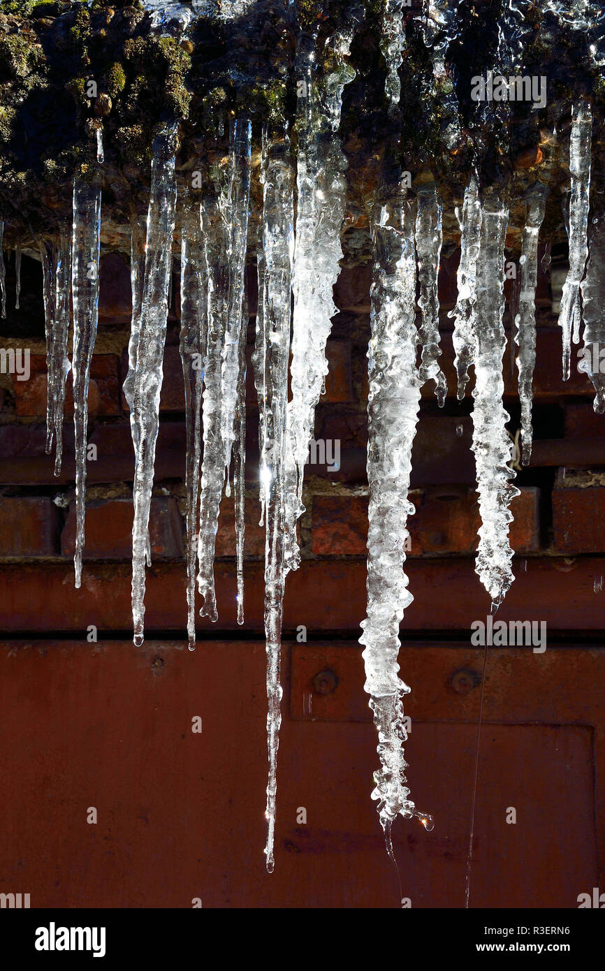 Eiszapfen hängen auf dem Dach in der Nähe bis zu tropfen. Schöne Element der Winter oder Frühling design Stockfoto
