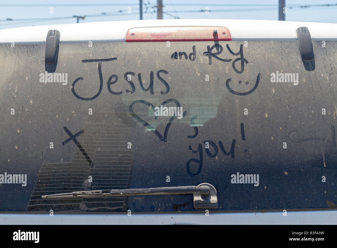 "Jesus liebt dich" in die schmutzige Heckscheibe eines geparkten Fahrzeug in der Innenstadt von San Diego, Kalifornien, USA geschrieben. Stockfoto