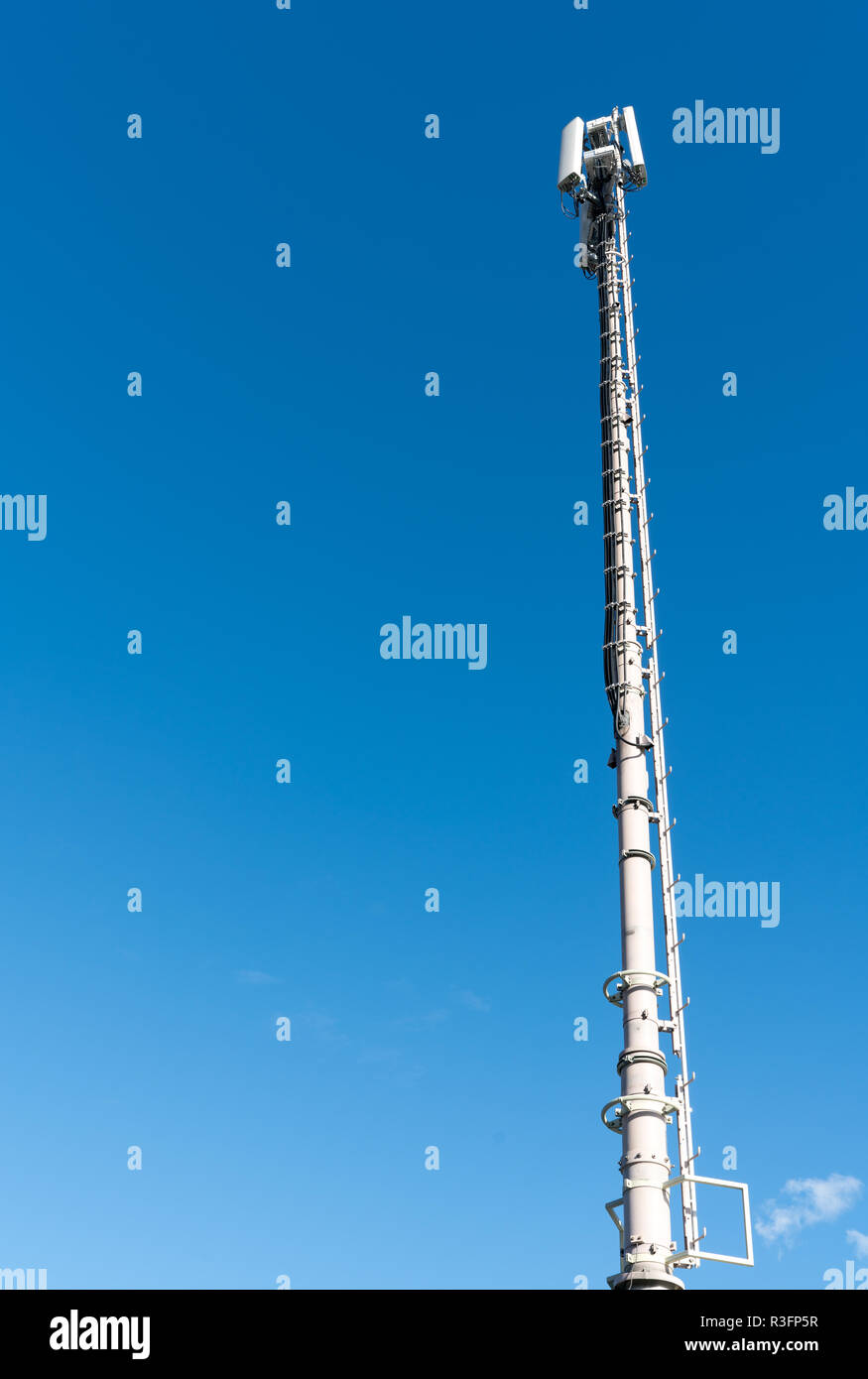 Vertikale Ansicht von einem hohen antennenmast für Mobile und Mobile Telefon Service mit einem blauen Himmel Hintergrund Stockfoto