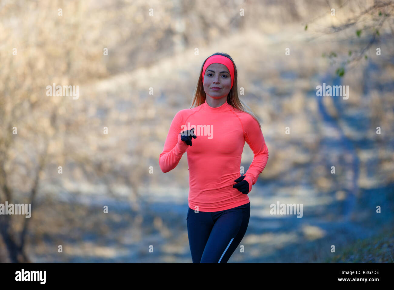 Junge schlanke Mädchen im Park läuft im frühen Winter. Attraktive Frau joggen auf verschneiten Trail Stockfoto