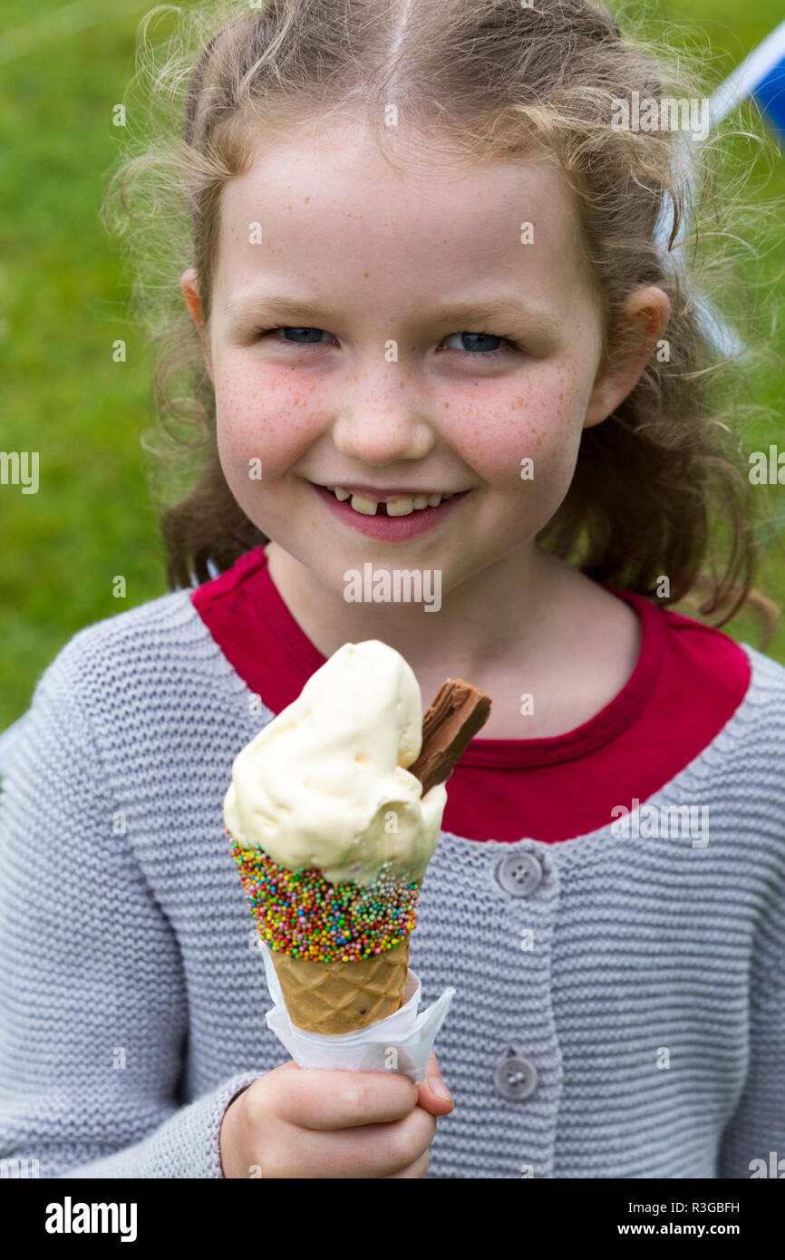 6-jähriges Mädchen/Kind/kid leckt ein Eis mit Hunderten und Tausenden und eine Schokolade Flake, während es schnell schmilzt. (98) Stockfoto