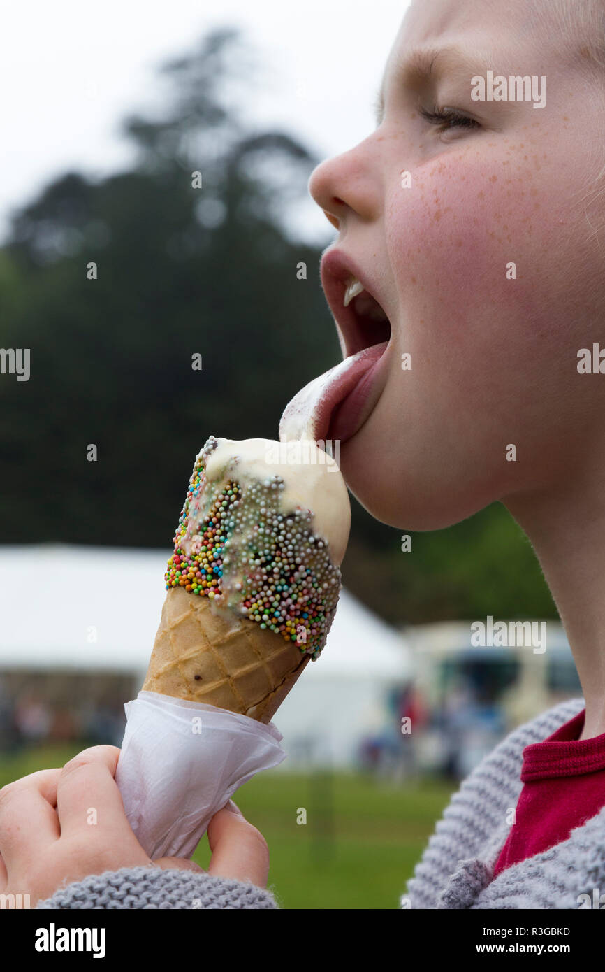 6-jähriges Mädchen/Kind/kid leckt ein Eis, mit Hunderten und Tausenden eingerichtet, während es schnell schmilzt. (98) Stockfoto
