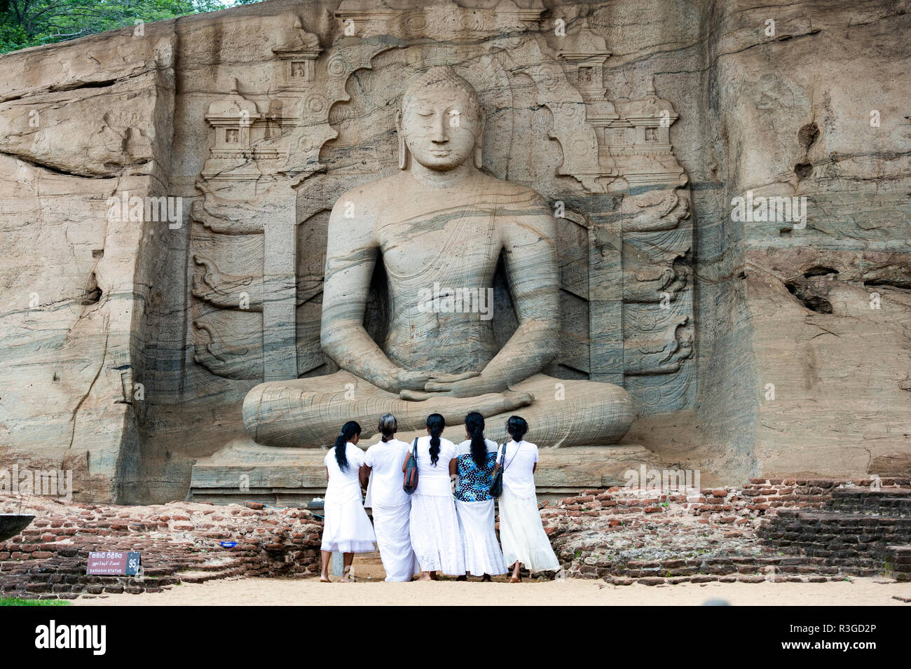 Fünf religiöse Frauen stehen und bewundern die große Samadhi Statue in Polonnaruwa, Sri Lanka. Stockfoto