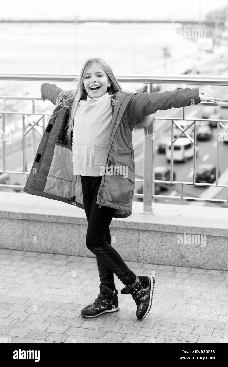 Kind im roten Mantel stand mit offenen Händen auf der Brücke. Mädchen mit blonden langen Haaren lächeln Outdoor. Abenteuer, Entdeckung, Reise. Kid genießen Herbst Tag auf Blu Stockfoto