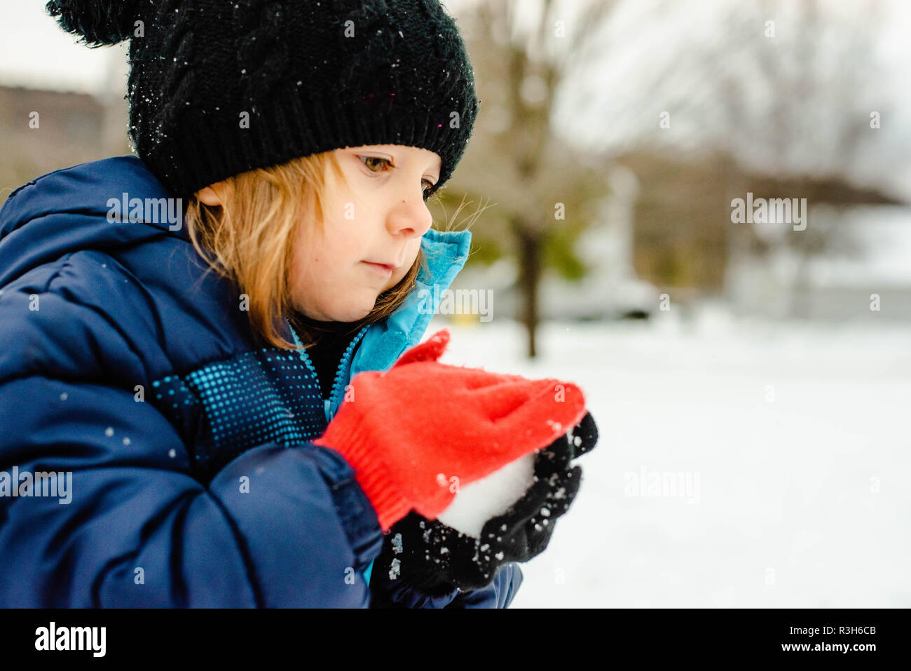 Ein kleines Mädchen spielt im Schnee An einem kalten Wintertag in den Vereinigten Staaten. Stockfoto