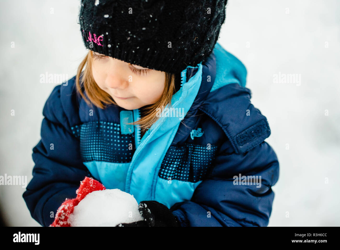 Ein kleines Mädchen spielt im Schnee An einem kalten Wintertag in den Vereinigten Staaten. Stockfoto