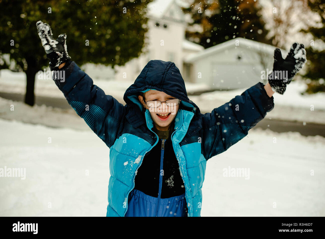 Die 12-jaehrige Junge wirft Schnee bis in die Luft an einem Wintertag im November in den Vereinigten Staaten. Stockfoto