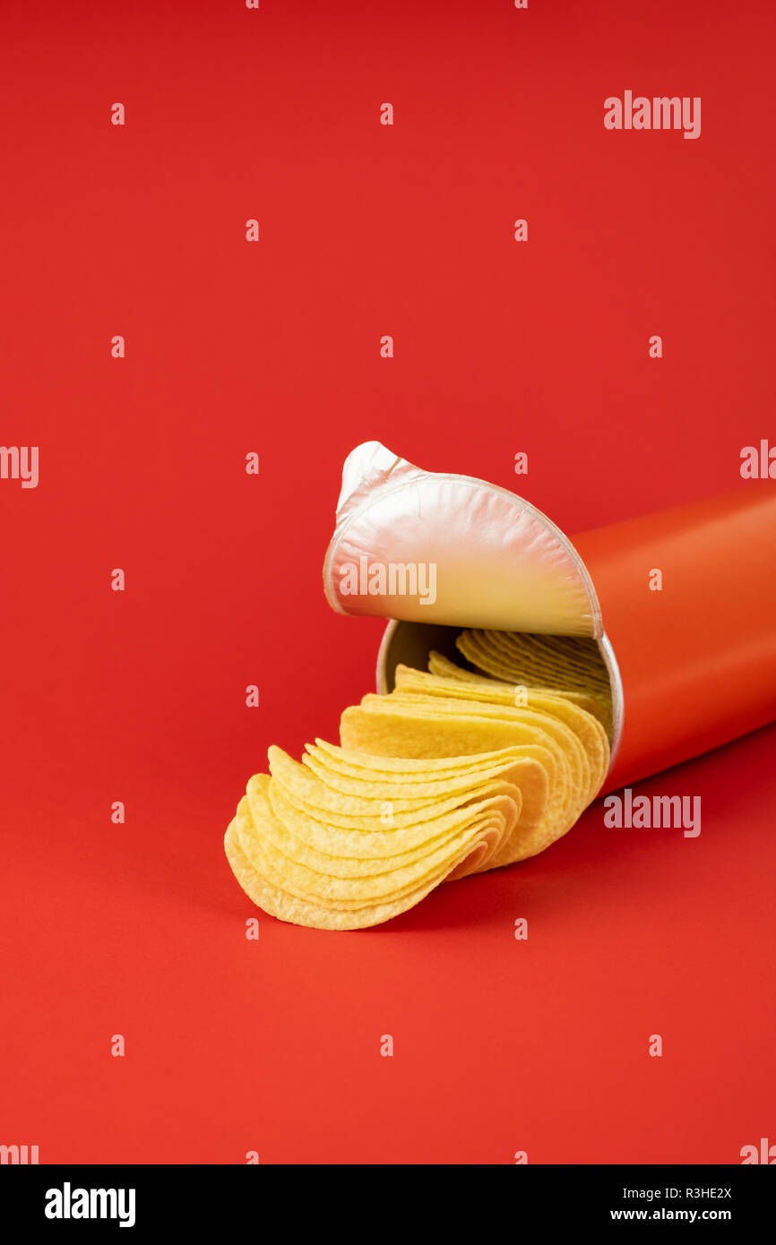 Kartoffelchips in hellen roten Hintergrund. Minimalistischer Bild von aufmerksamkeitsstarke Snacks in lebendigen Farben Stockfoto