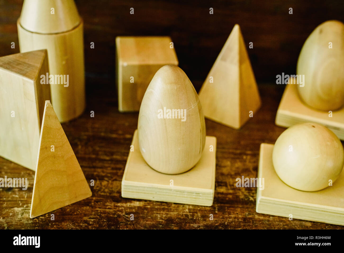 Massivholz formen Geometrie und Volumes, Kegel, Dreiecke, Quadrate zu studieren, Kugeln auf einem warmen Holz Hintergrund. Stockfoto