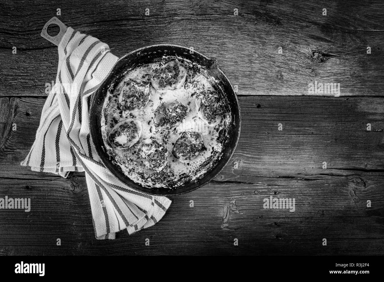 Konzept: Hausmannskost. Pfanne mit gebratenem Schnitzel mit Sauce und eine Küche Serviette auf einem Holztisch. Ansicht von oben Stockfoto