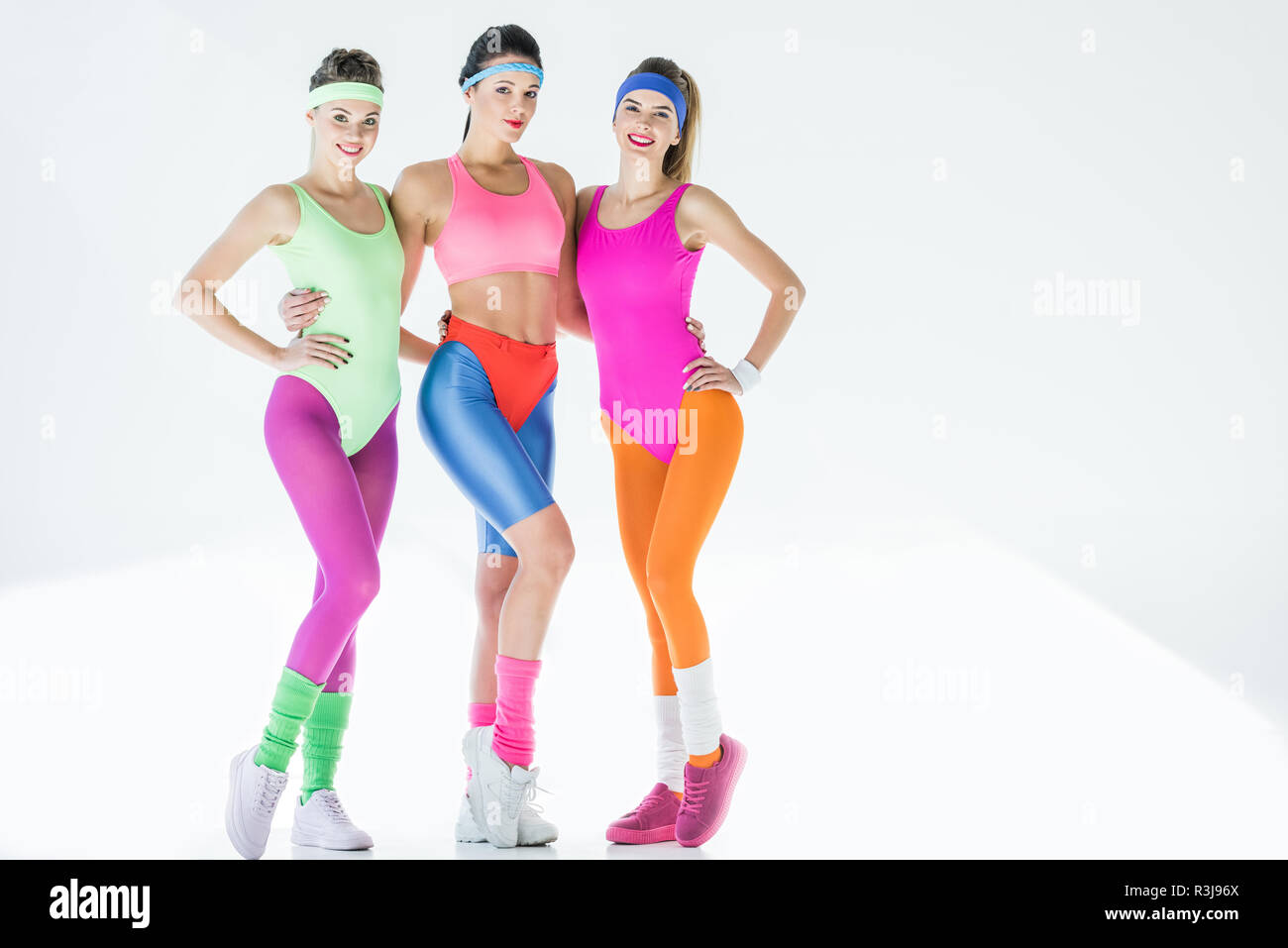 Attraktive Junge Frauen Im 80er Jahre Stil Sportswear Zusammen Stehen Und Lachelte Kamera Auf Grau Stockfotografie Alamy