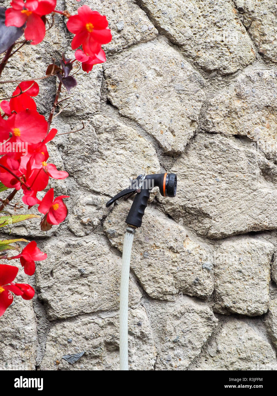 Ein Garten Wasser Spritzdüse an einem Nagel auf einer Steinmauer. Stockfoto