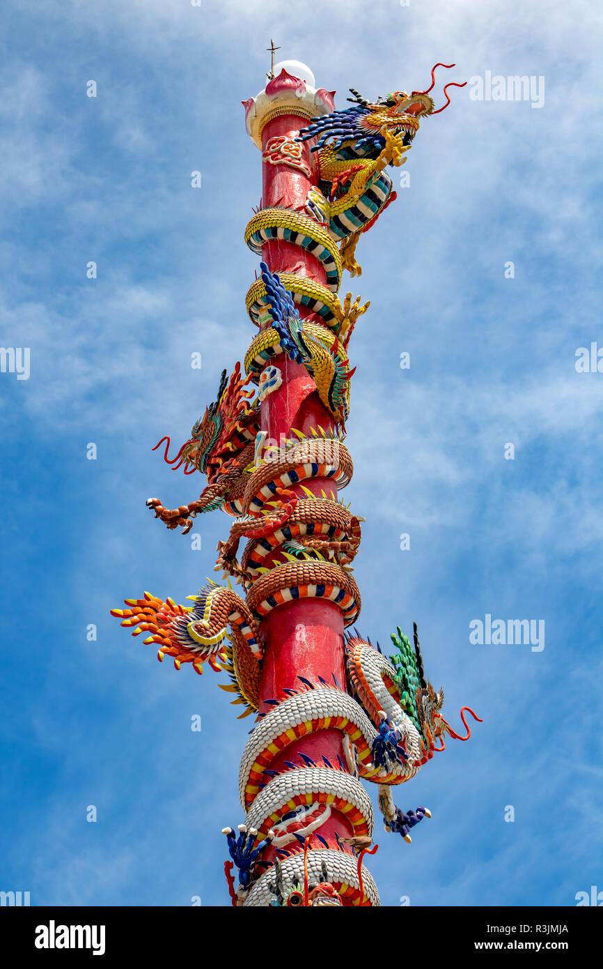 Die Säule der Drachen in der chinesischen Tempel. Traditionelle Drachen Spalte mit bunten Dekoration gegen den blauen Himmel, Thailand. Stockfoto