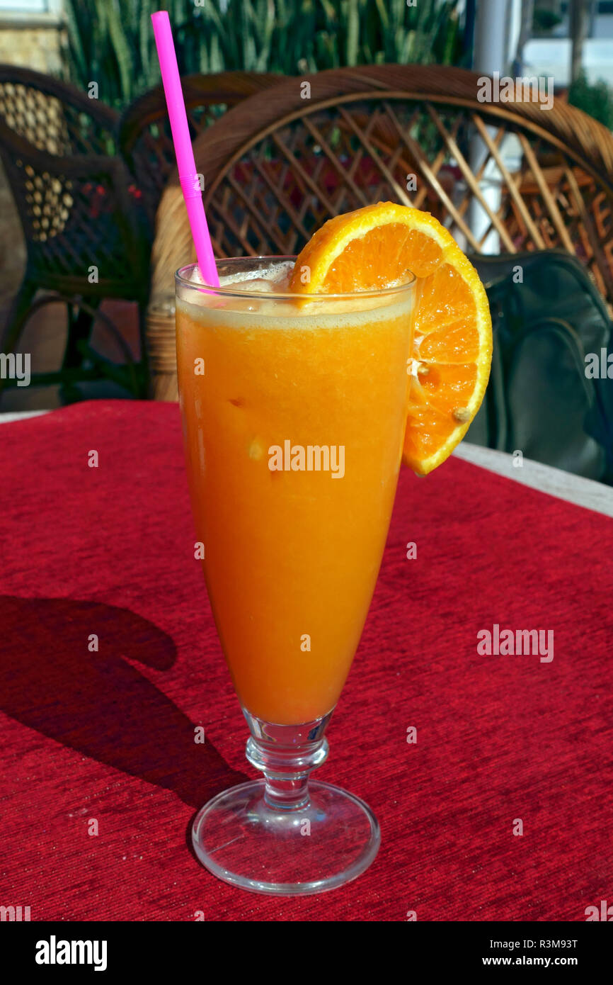 Glas frisch gepressten Orangensaft mit einem Kunststoff Stroh Stockfoto