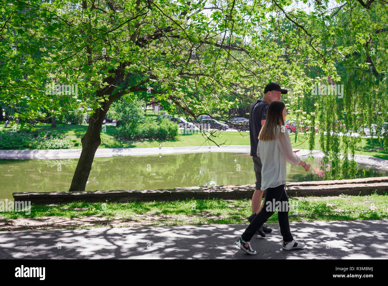 Park sonnige junge Menschen, Blick auf zwei junge Menschen zu Fuß durch den Park im Karola Marcinkowskiego an einem Sommermorgen, Posen, Polen. Stockfoto