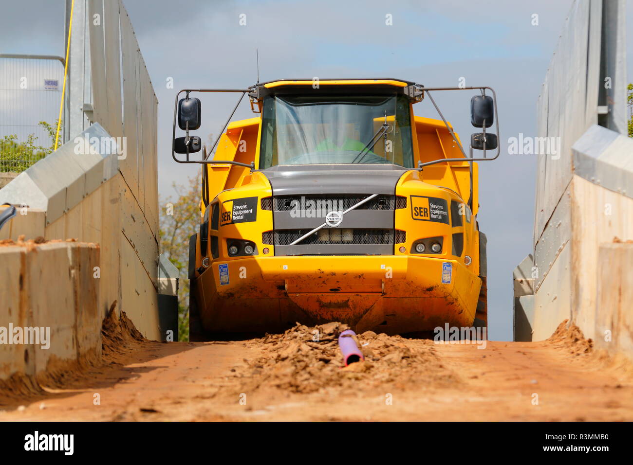 Ein Knickgelenkter Dumper drückt über einem schmalen Eisenbahnbrücke über den Bau von Iport in Rossington, Doncaster, South Yorkshire. Stockfoto