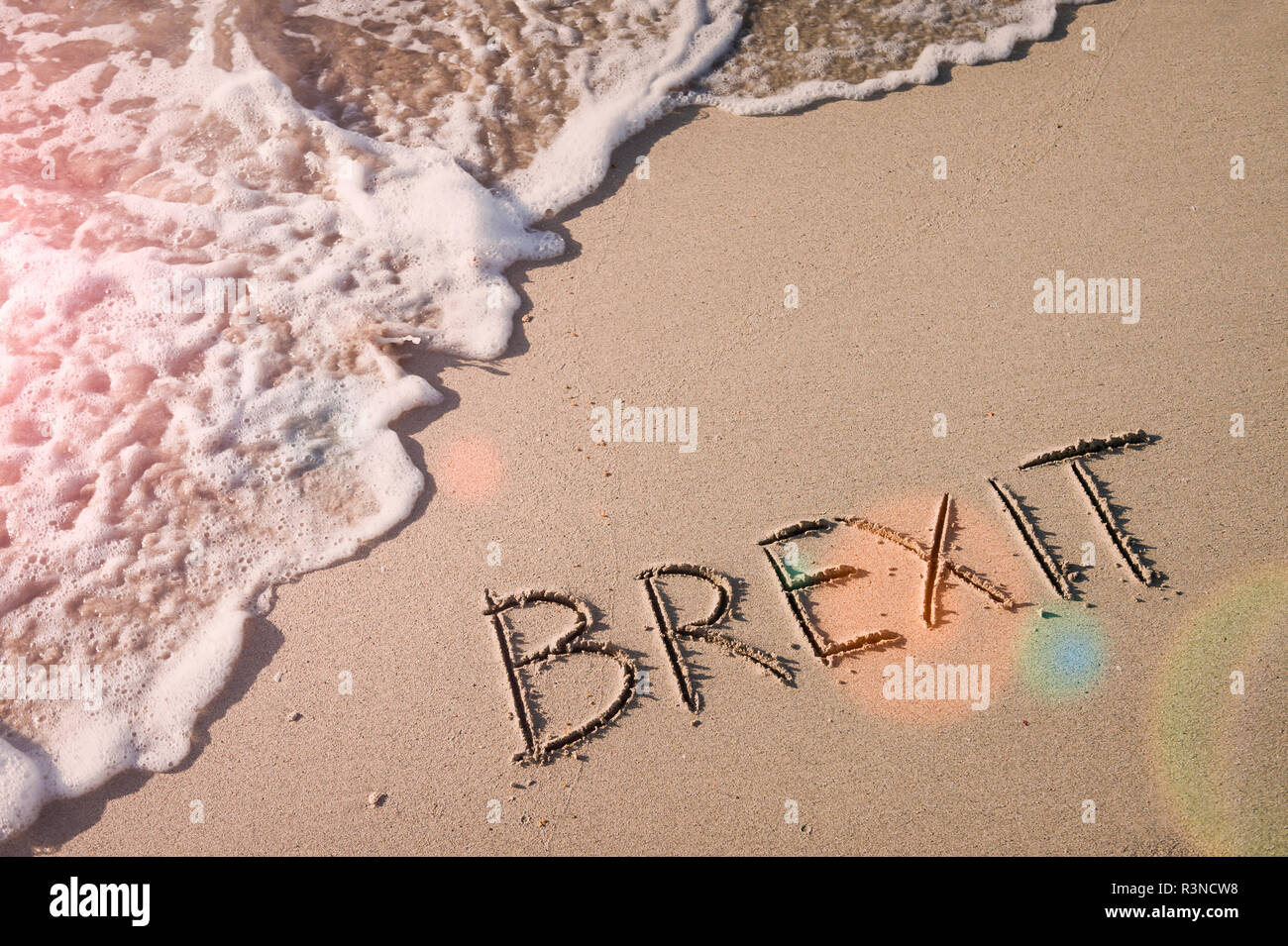 Inspirational Brexit Nachricht handschriftlich in sanften Sand mit sonnigen lens flare oben ankommenden Wellen Stockfoto
