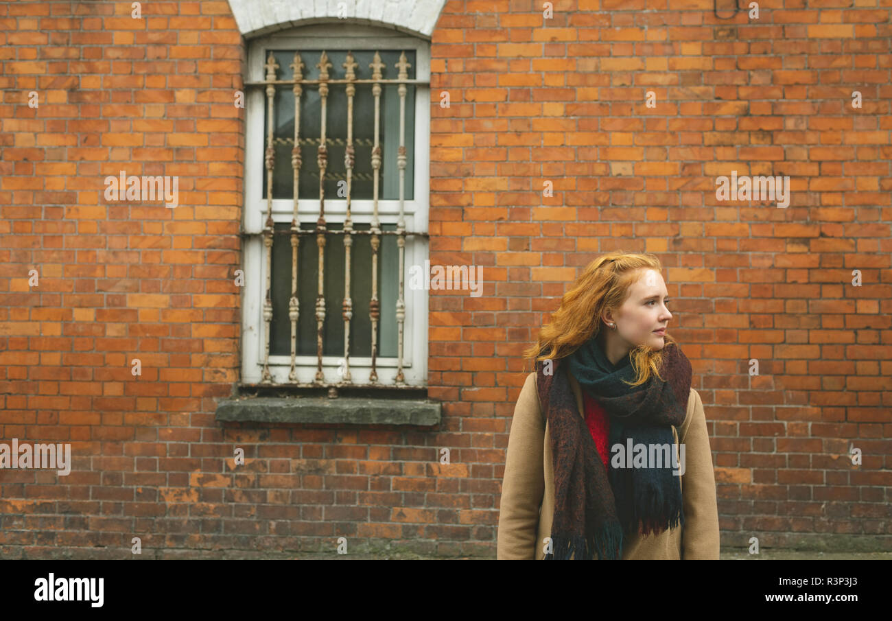 Frau, die mit der Hand in der Tasche gegen die Mauer Stockfoto