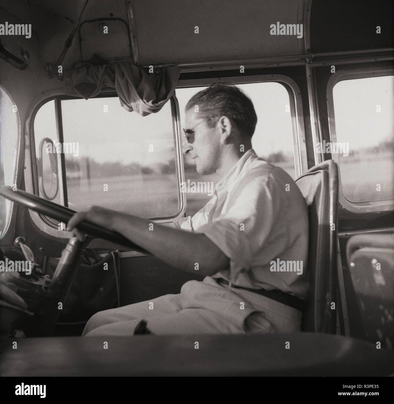 1950 s, historischen, einen männlichen Trainer Fahrer sitzt mit seinen Händen am Lenkrad seines Verkehr, Europa. Stockfoto