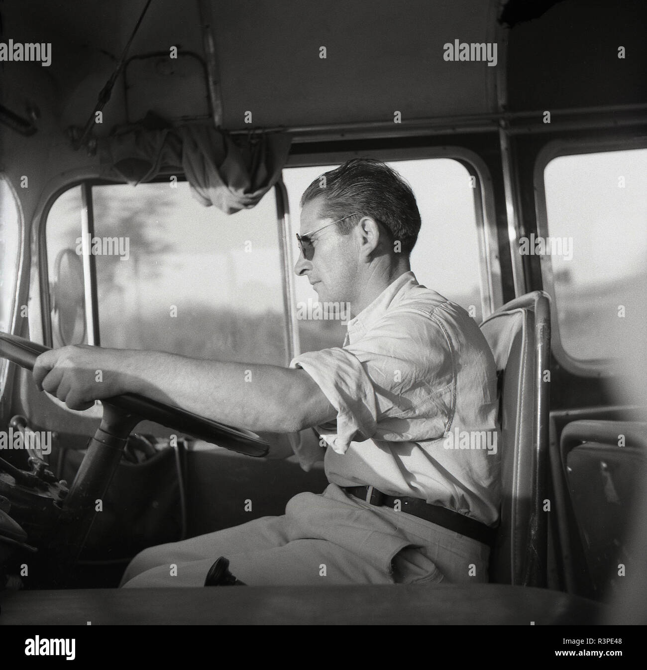 1950 s, historischen, einen männlichen Trainer Fahrer sitzt mit seinen Händen am Lenkrad seines Verkehr, Europa. Stockfoto