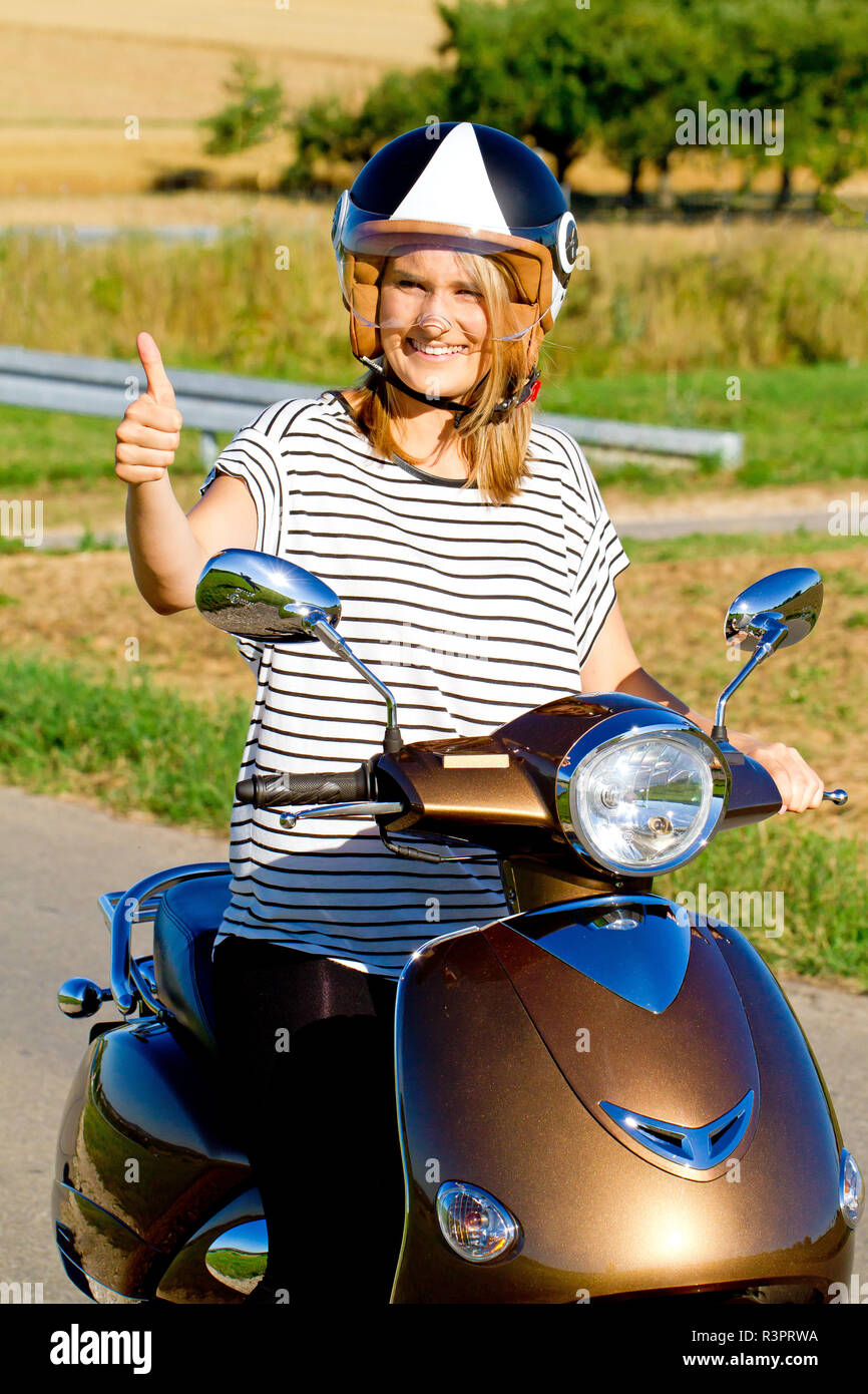 Junge Frau mit Daumen oben auf dem motorroler Stockfoto