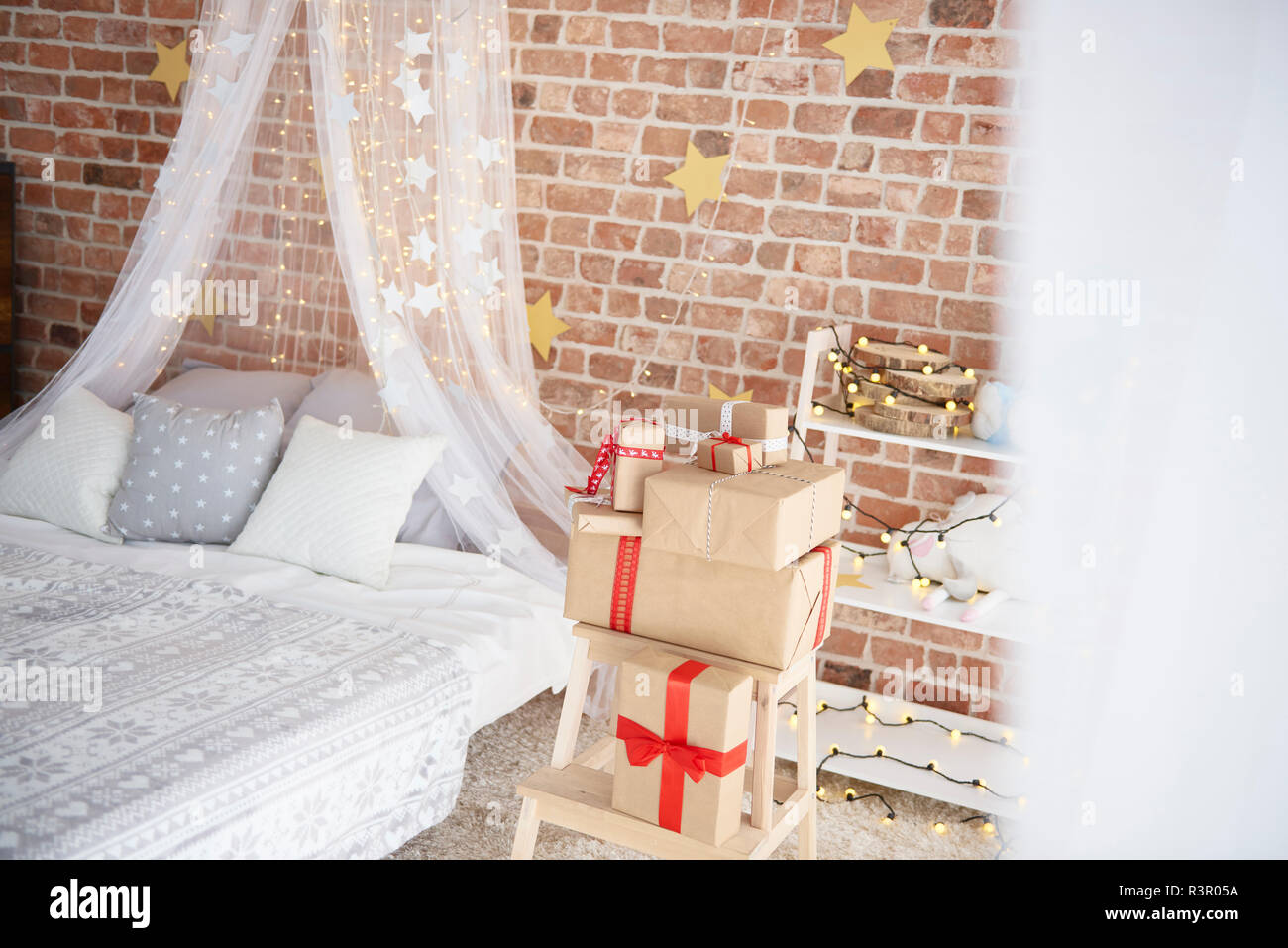 Gemütliches Schlafzimmer mit Weihnachtsbeleuchtung und präsentiert Stockfoto