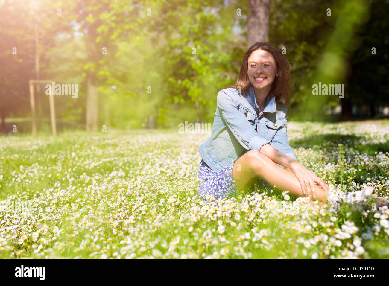 Lächelnde junge Frau im Park sitzen Stockfoto