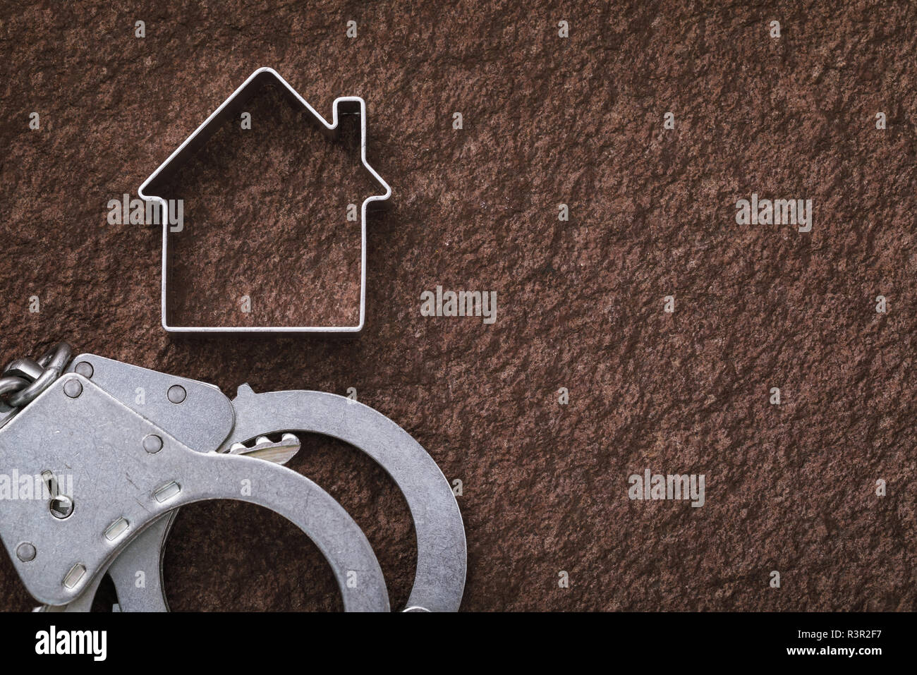 Handschellen und eine Figur in der Form eines Hauses auf Stein Oberfläche mit kopieren. Konzept der Immobilien Betrug Stockfoto