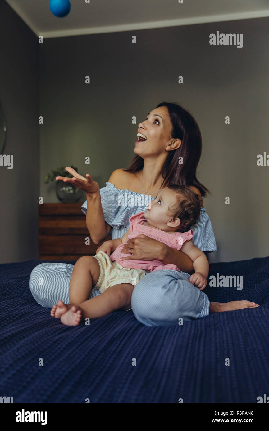 Glückliche Mutter spielt mit ihrem Baby Mädchen auf dem Bett Stockfoto