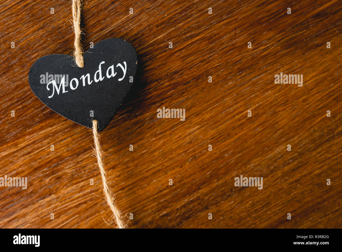 Herzen von schwarzem Holz mit Tag der Woche, am Montag. Stockfoto