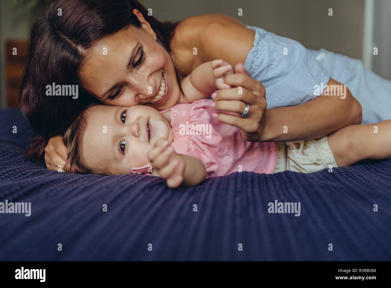 Glückliche Mutter kuscheln mit ihrem Baby Mädchen auf dem Bett Stockfoto