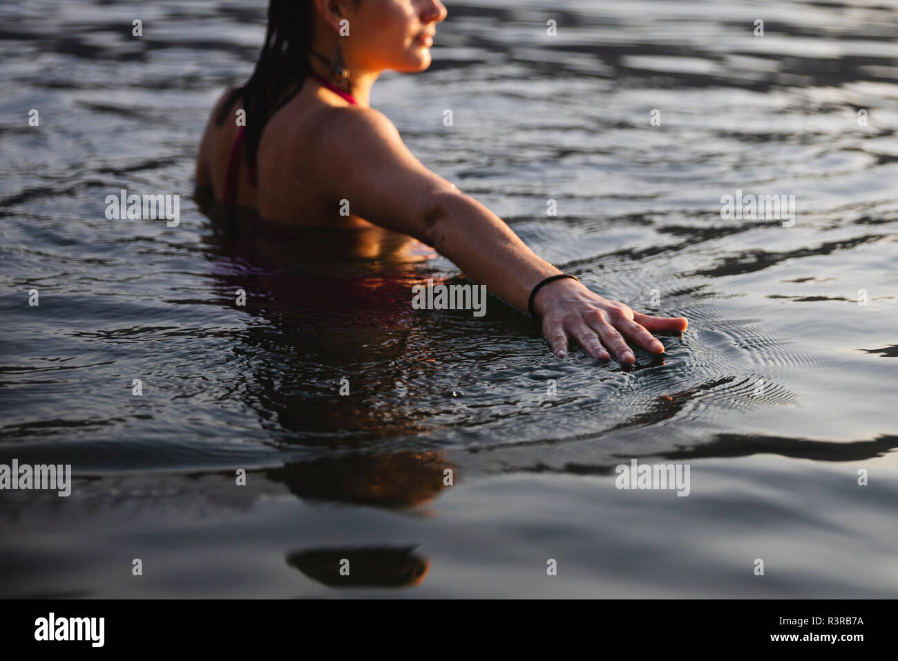 Die Hand der jungen Frau berühren der Wasseroberfläche in einem See Stockfoto