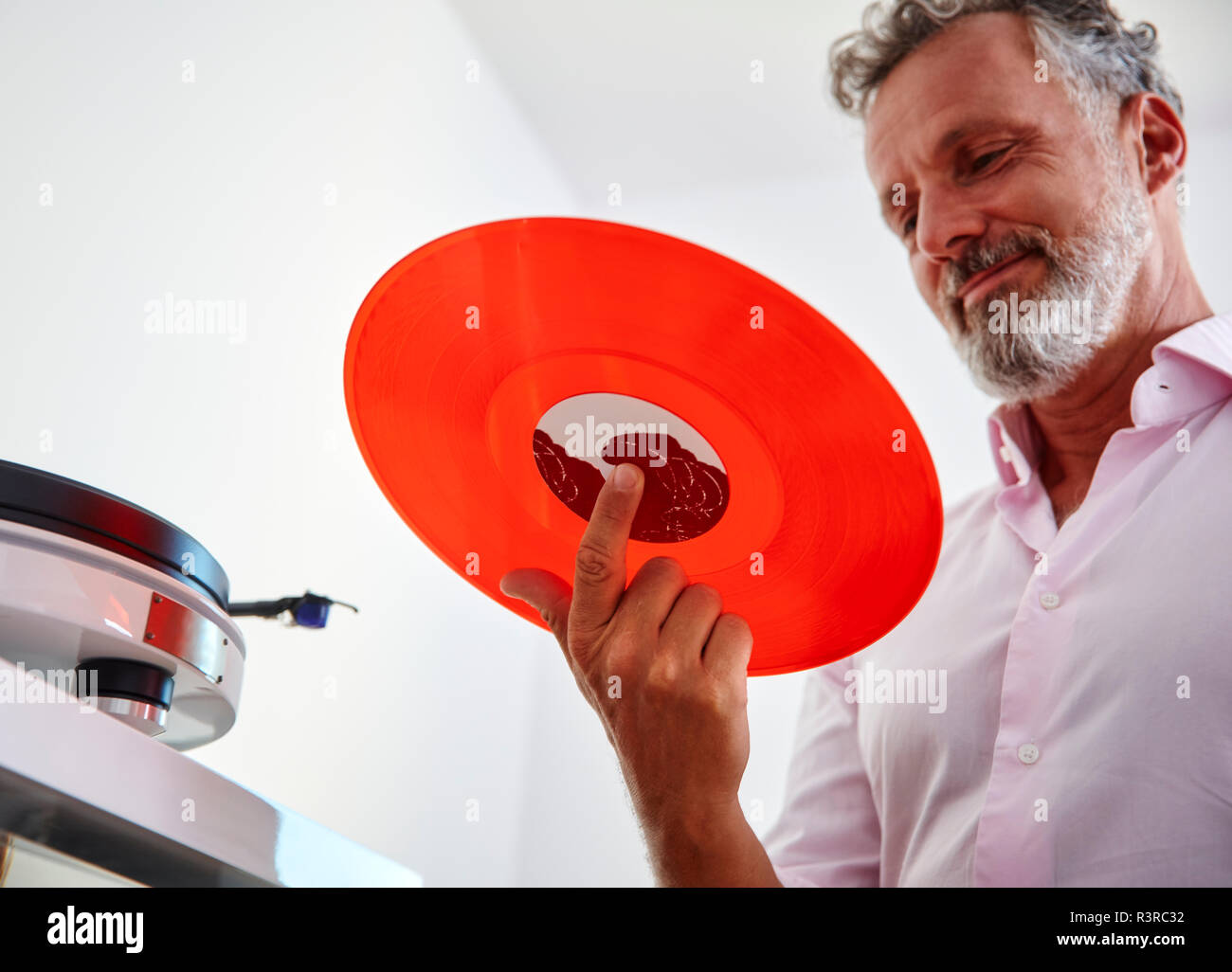 Lächelnd reifer Mann mit roten Vinyl record Stockfoto