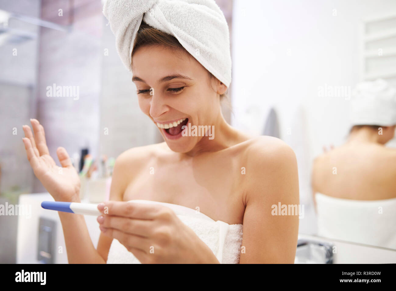 Portrait der aufgeregten Jungen Frau an der Schwangerschaft Test im Badezimmer suchen Stockfoto