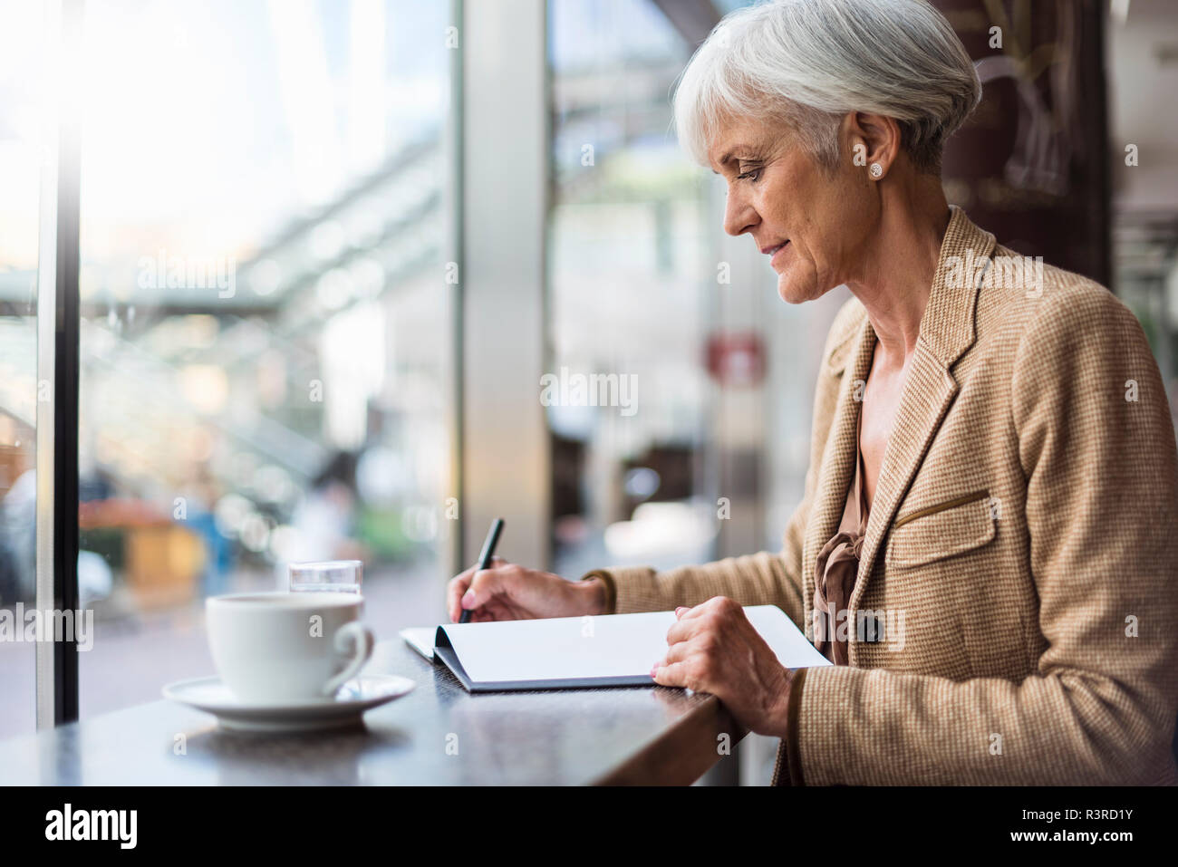 Senior Geschäftsfrau Notizen in einem Cafe Stockfoto