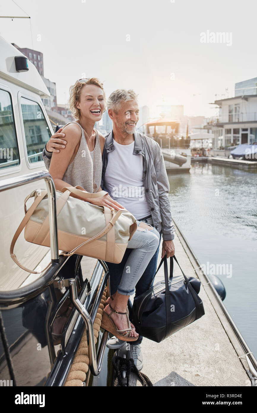 Alter Mann und junge Frau, die mit dem reisen Beutel auf Steg neben Yachtcharter Stockfoto
