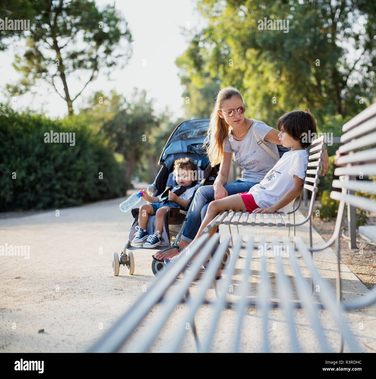Mutter sitzen auf einer Parkbank, im Gespräch mit einem ihrer Söhne Stockfoto