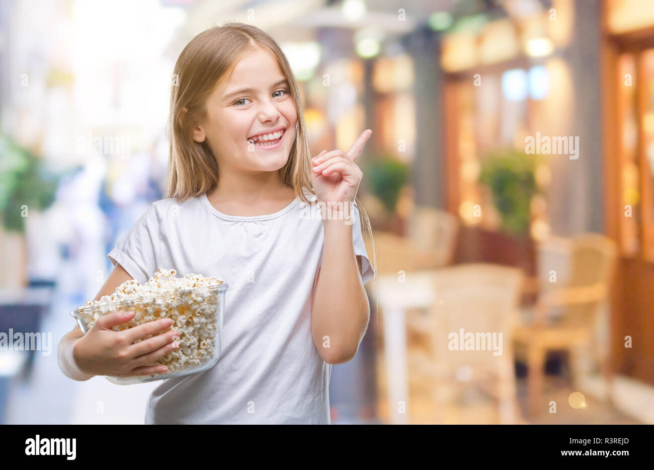 Junge schöne Mädchen essen Popcorn snack isoliert Hintergrund sehr zufrieden zeigt mit Finger- und an der Seite Stockfoto