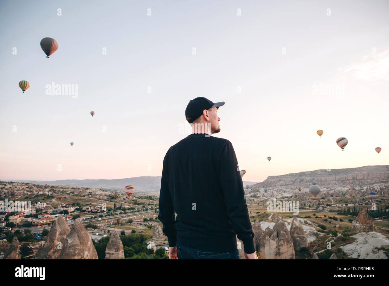 Ein Mann, der in der Einsamkeit bewundert einen schönen Blick auf das fliegende Ballons in Kappadokien in der Türkei. Stockfoto
