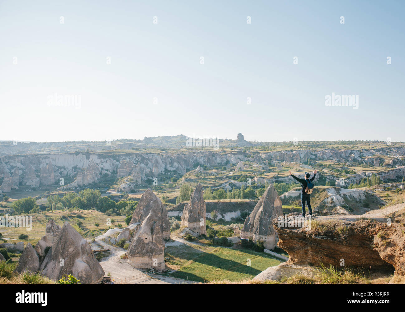 Ein Mann steht auf einem Berg in der Einsamkeit, bewundert die schöne Aussicht auf die Naturlandschaft in Kappadokien in der Türkei und hebt seine Hände bis zu zeigen, wie er frei und glücklich. Stockfoto