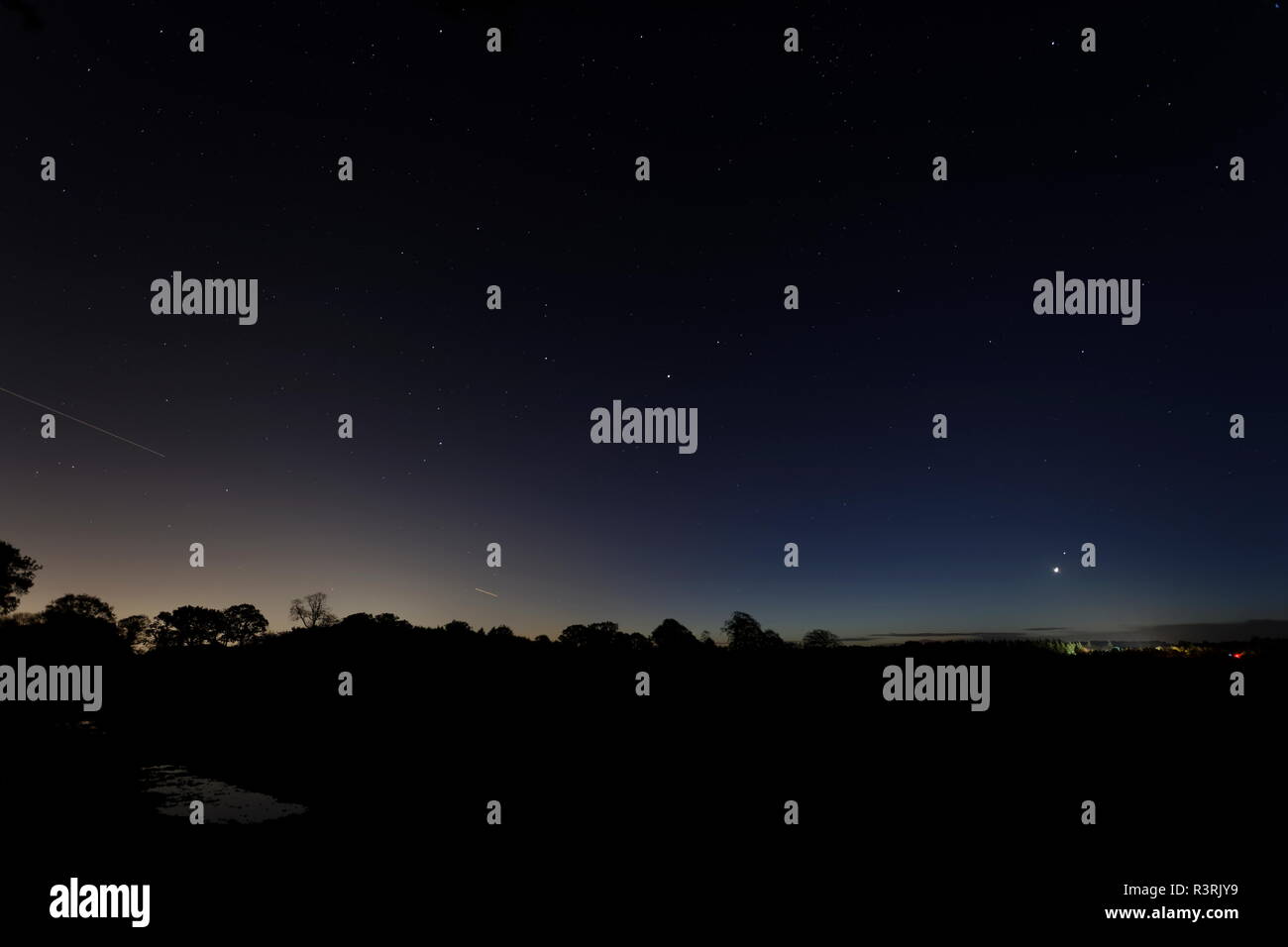 Venus beherrscht das Morgengrauen, als sie gerade über den Horizont steigt mit dem Stern Spica oberhalb vom Sternbild Jungfrau eine entfernte Farm leuchtet u Stockfoto