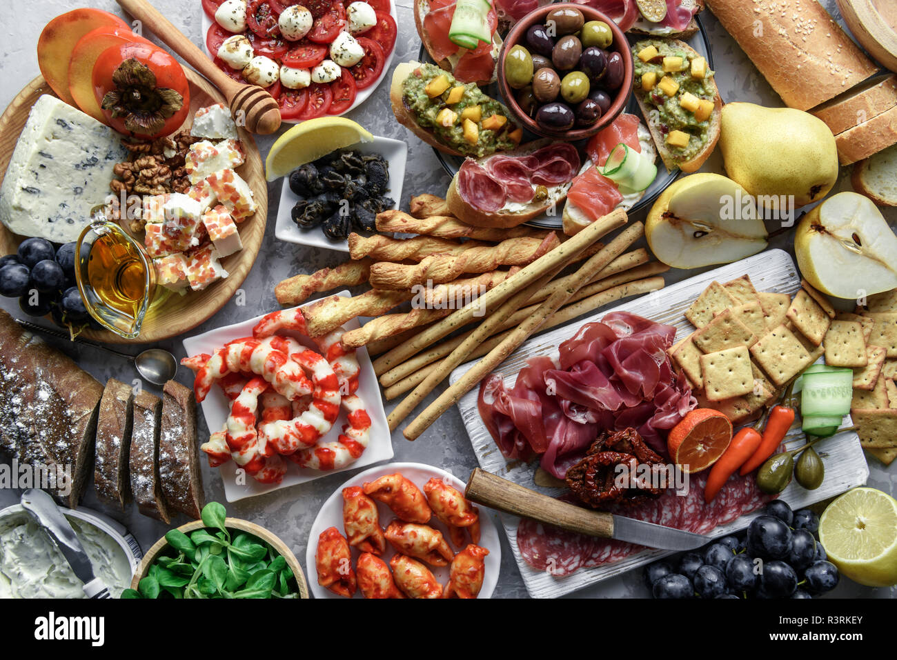 Italienische Antipasti Snacks. Brushettas, Käse Vielfalt, Garnelen, Lachs, Oliven, Schinken mit Birne, Salami und Schinken über Graues grunge Tabelle Stockfoto