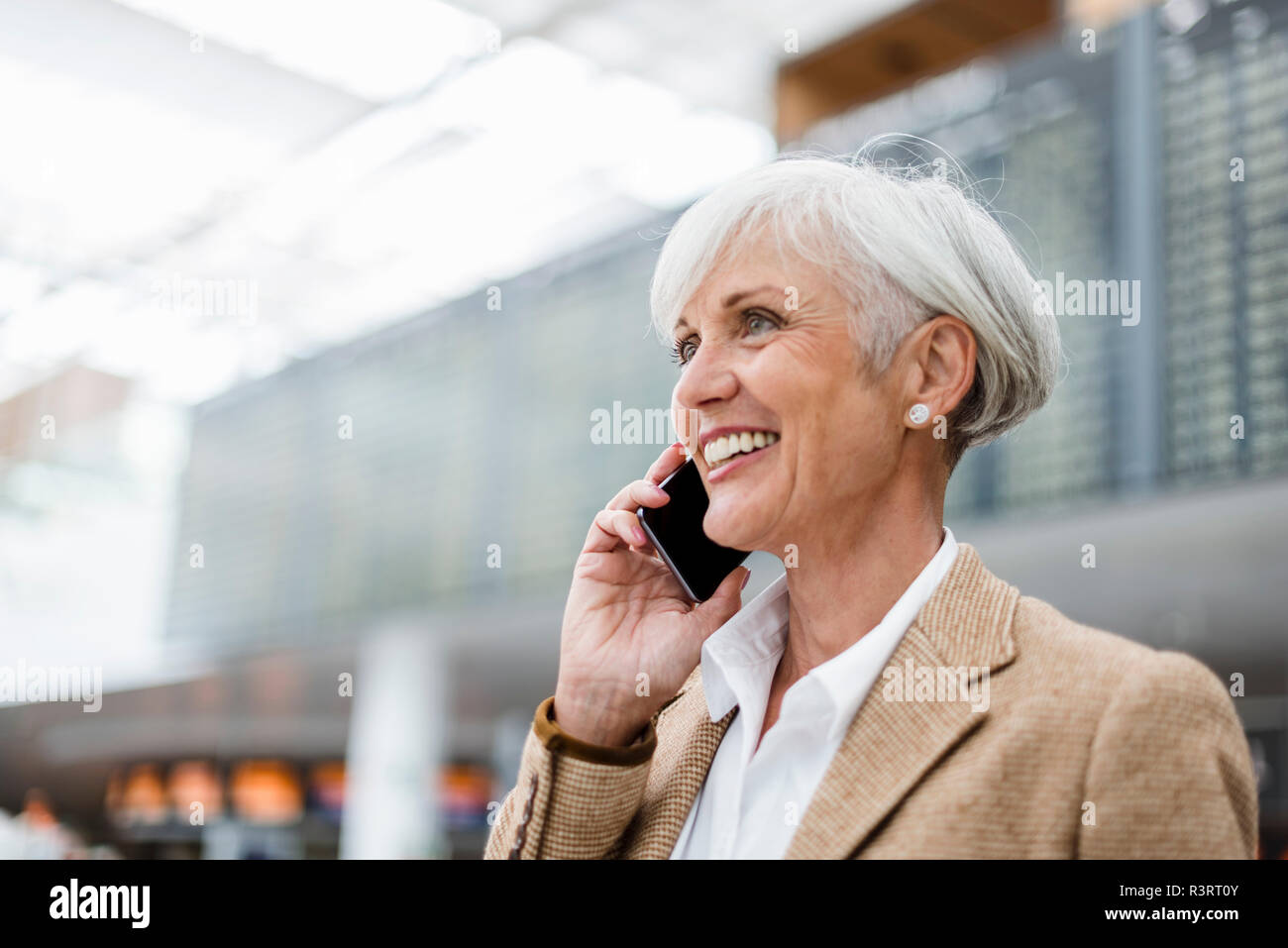 Lächelnd senior Geschäftsfrau auf Handy am Flughafen Stockfoto
