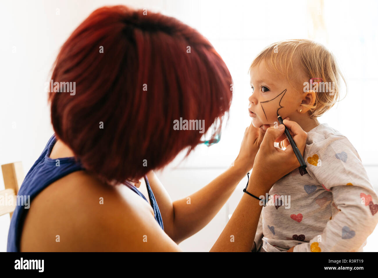 Mutter Malerei Gesicht ihrer Tochter für Halloween Stockfoto