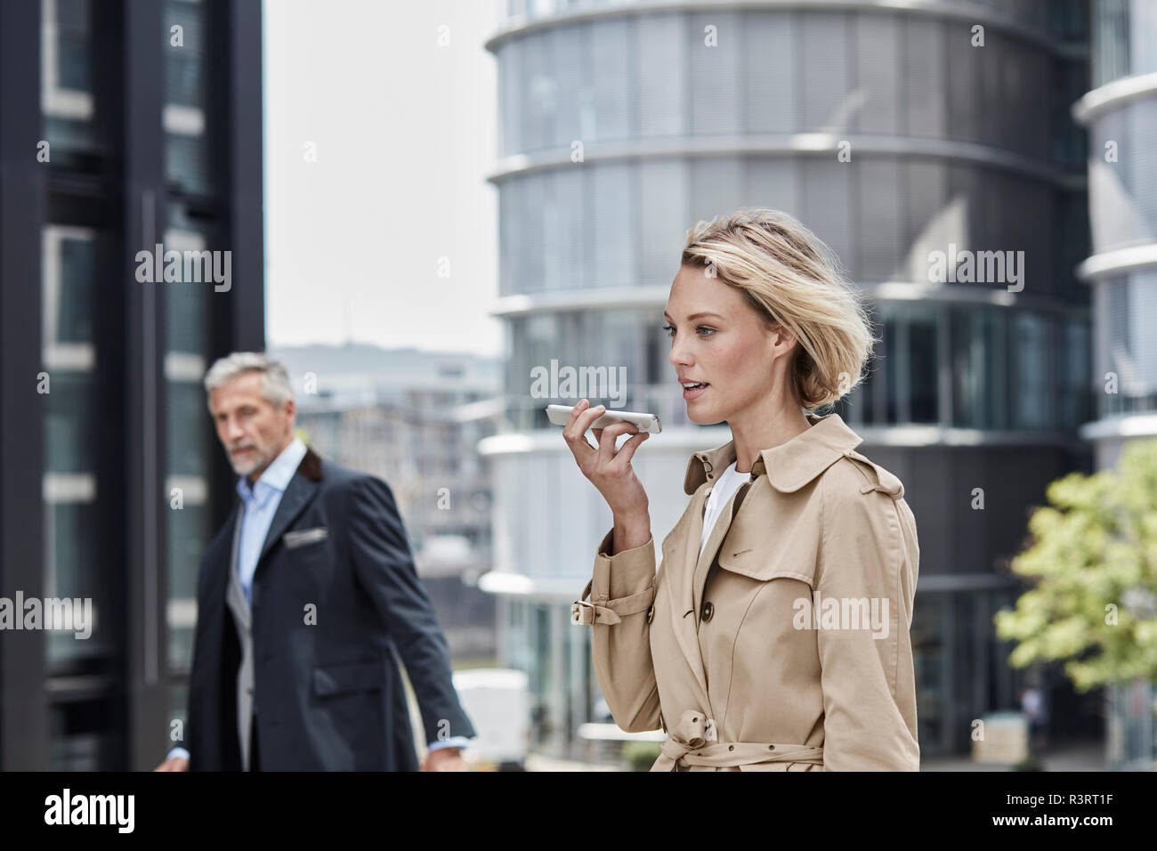 Deutschland, Duesseldorf, Porträt des Blonden Geschäftsfrau tragen beige trenchcoat Gespräch am Handy Stockfoto