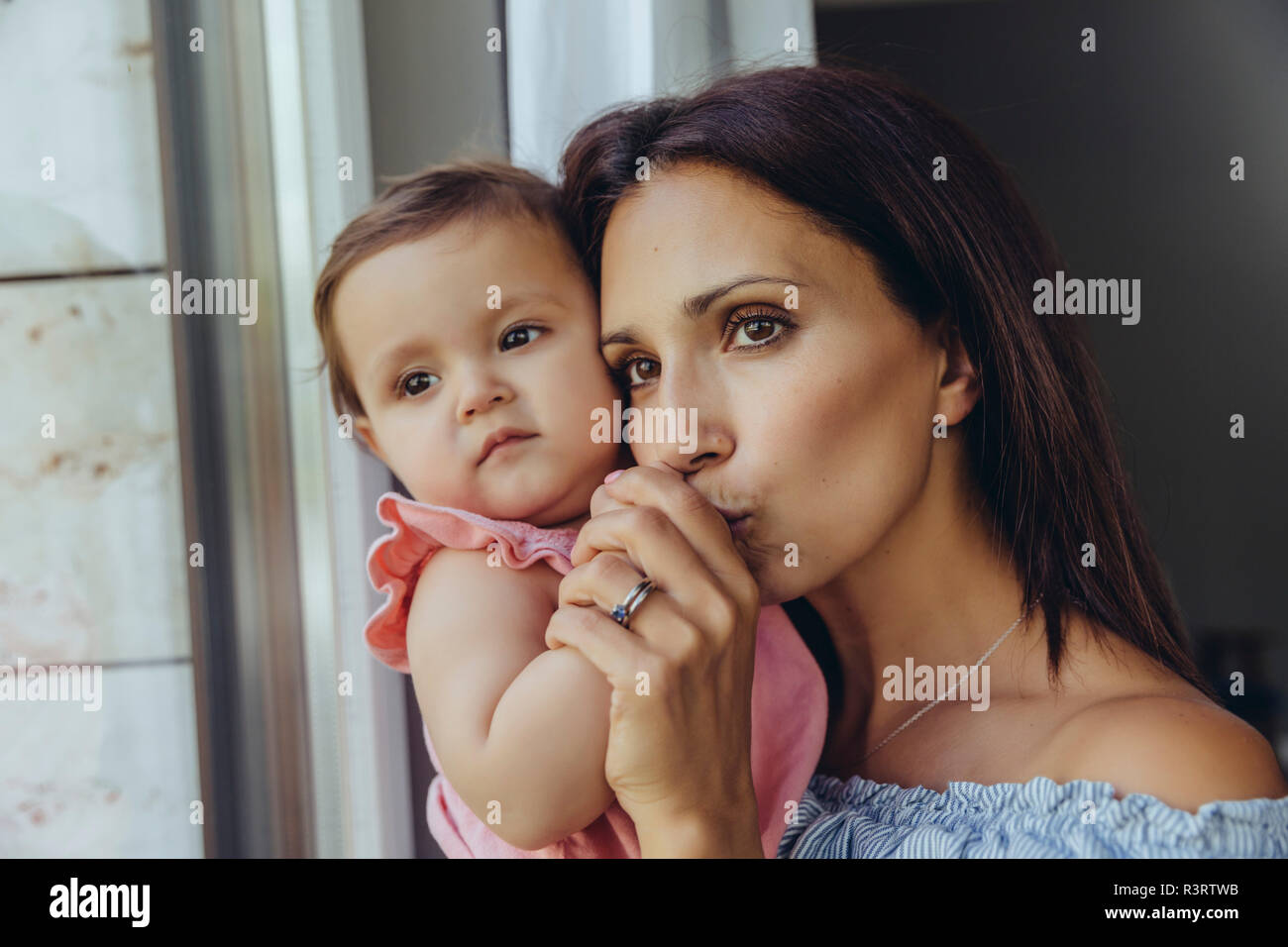 Mutter Blick aus Fenster mit Baby Tochter zu Hause Stockfoto