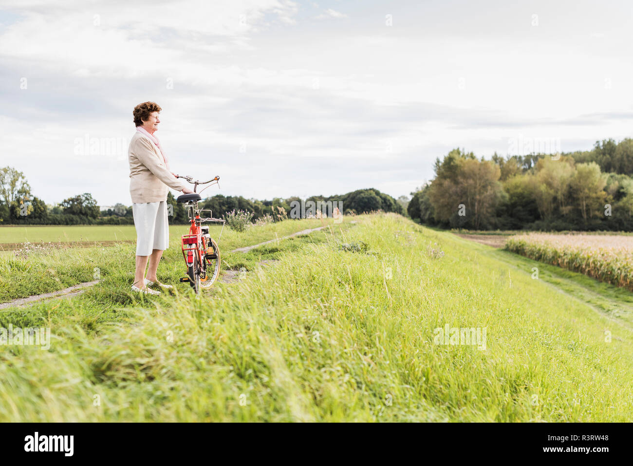 Ältere Frau mit Fahrrad in ländlichen Landschaft Stockfoto