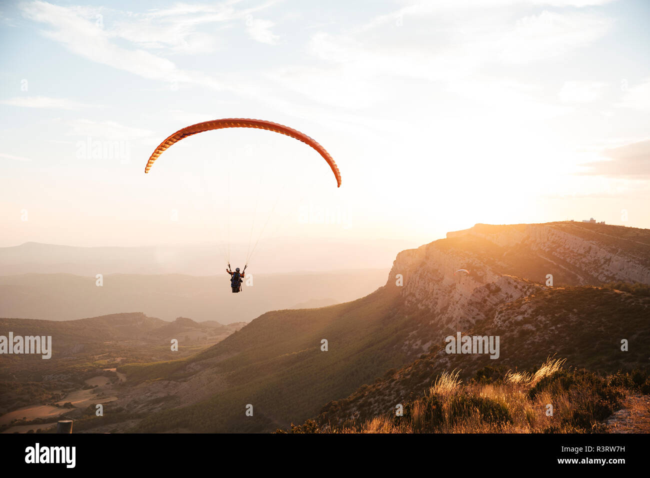 Spanien, Silhouette von Gleitschirm soaring hoch über die Berge bei Sonnenuntergang Stockfoto